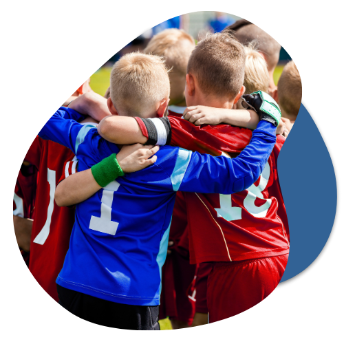 Children in sports jerseys embracing in a team huddle, symbolizing community spirit and teamwork in local sports initiatives.